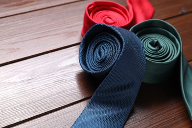 Photo of Different neckties on wooden table, closeup. Space for text