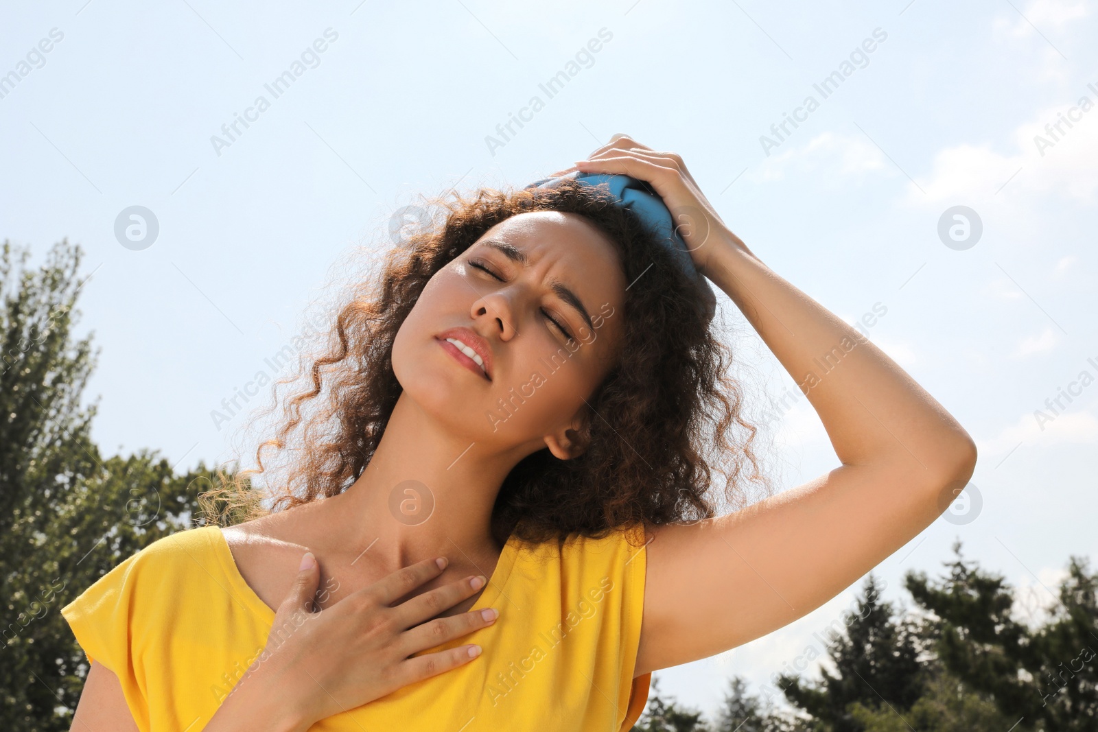 Photo of African-American woman with cold pack suffering from heat stroke outdoors