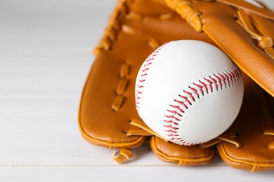 Photo of Leather baseball glove with ball on white wooden table, closeup. Space for text