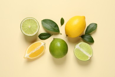 Fresh ripe lemons, limes and green leaves on beige background, flat lay