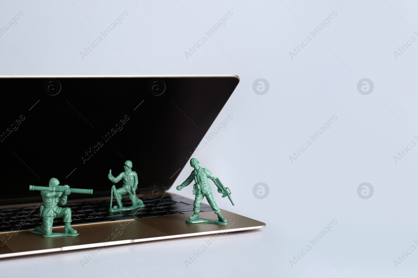 Photo of Hybrid warfare concept, online information battle. Laptop and toy soldiers on light grey background