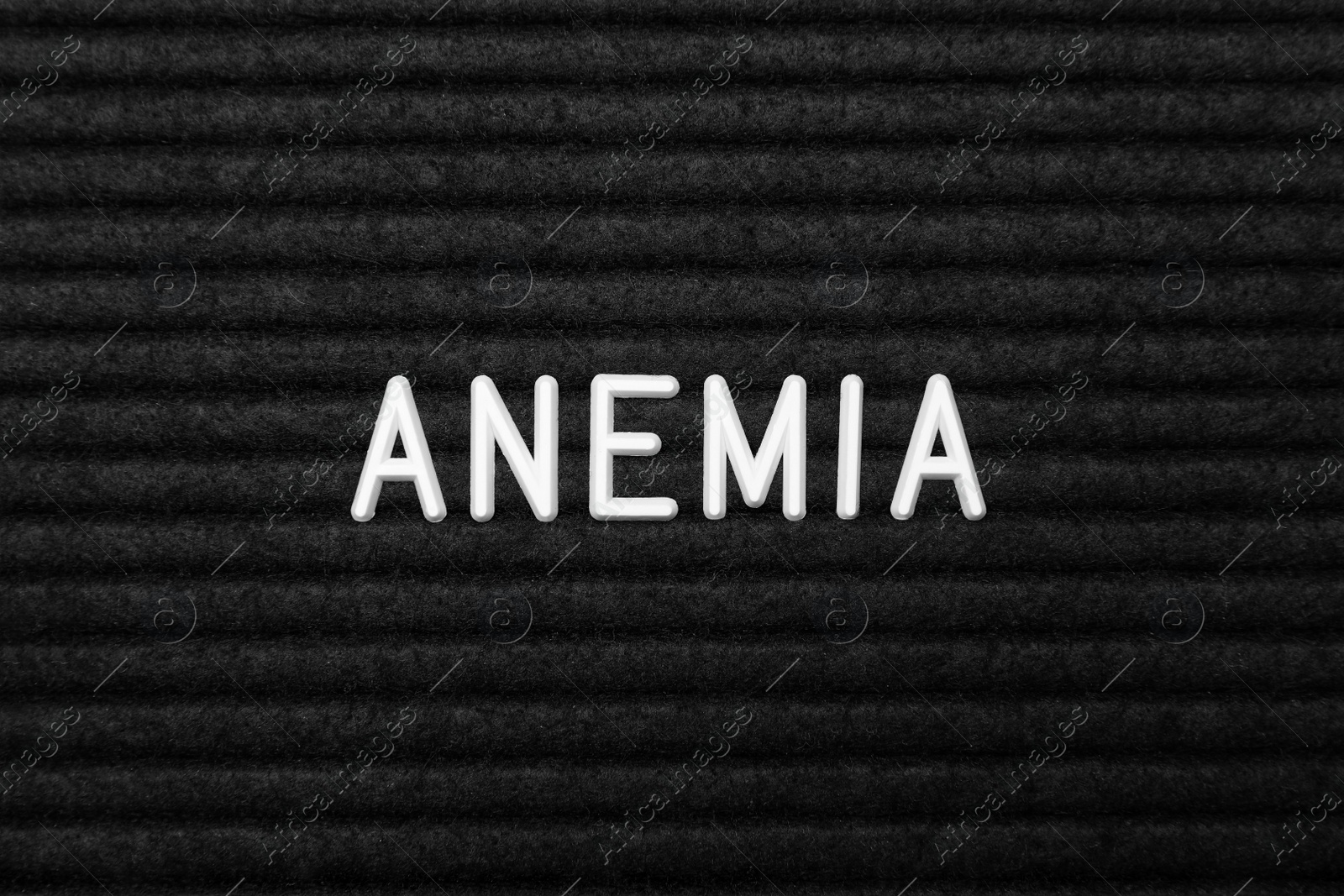 Photo of Word Anemia on black fabric, flat lay