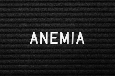 Photo of Word Anemia on black fabric, flat lay