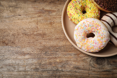 Delicious glazed donuts on wooden table, top view. Space for text