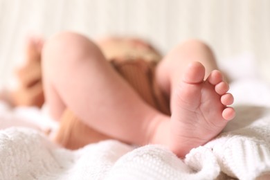 Photo of Cute newborn baby lying on white knitted plaid, closeup of legs. Space for text