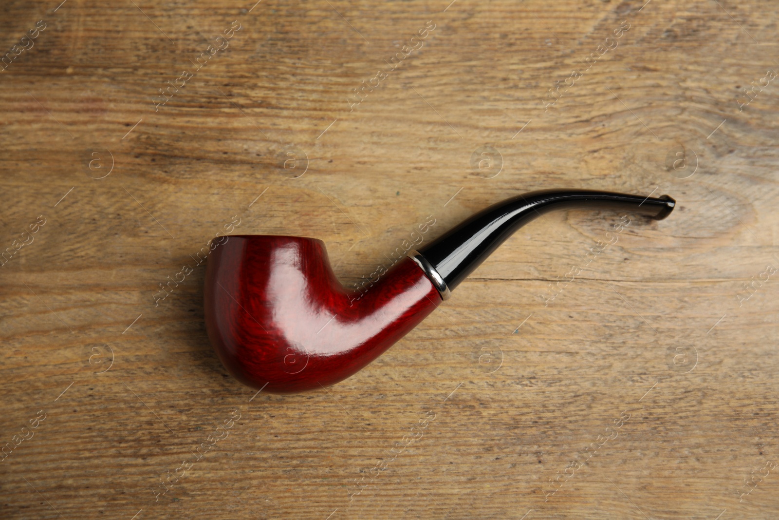 Photo of Classic smoking pipe on wooden table, top view