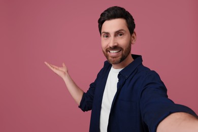 Photo of Smiling man taking selfie on pink background, space for text