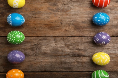 Decorated Easter eggs and space for text on wooden background, top view