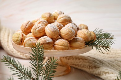 Photo of Delicious nut shaped cookies and fir tree branches on table, closeup