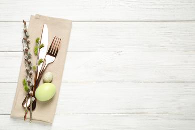 Cutlery set and beautiful willow branches on white wooden table, top view with space for text. Easter celebration