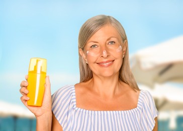 Sun protection. Beautiful mature woman with bottle of sunblock on beach