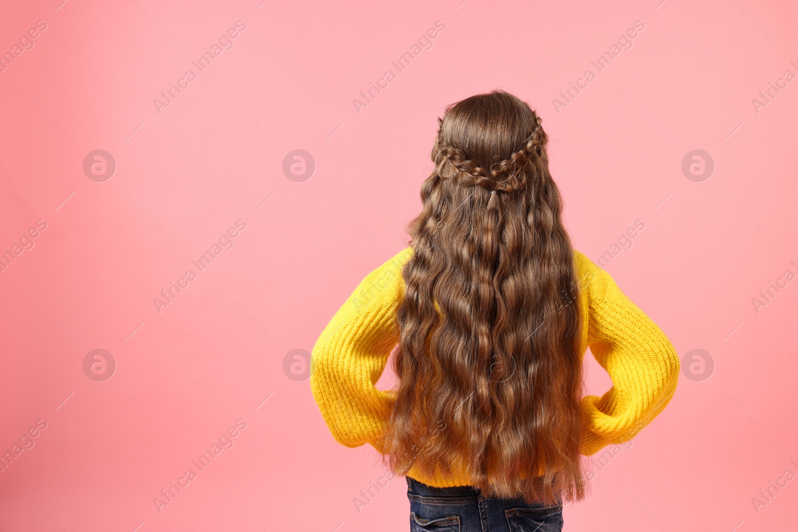 Photo of Little girl with braided hair on pink background, back view. Space for text