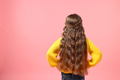 Photo of Little girl with braided hair on pink background, back view. Space for text