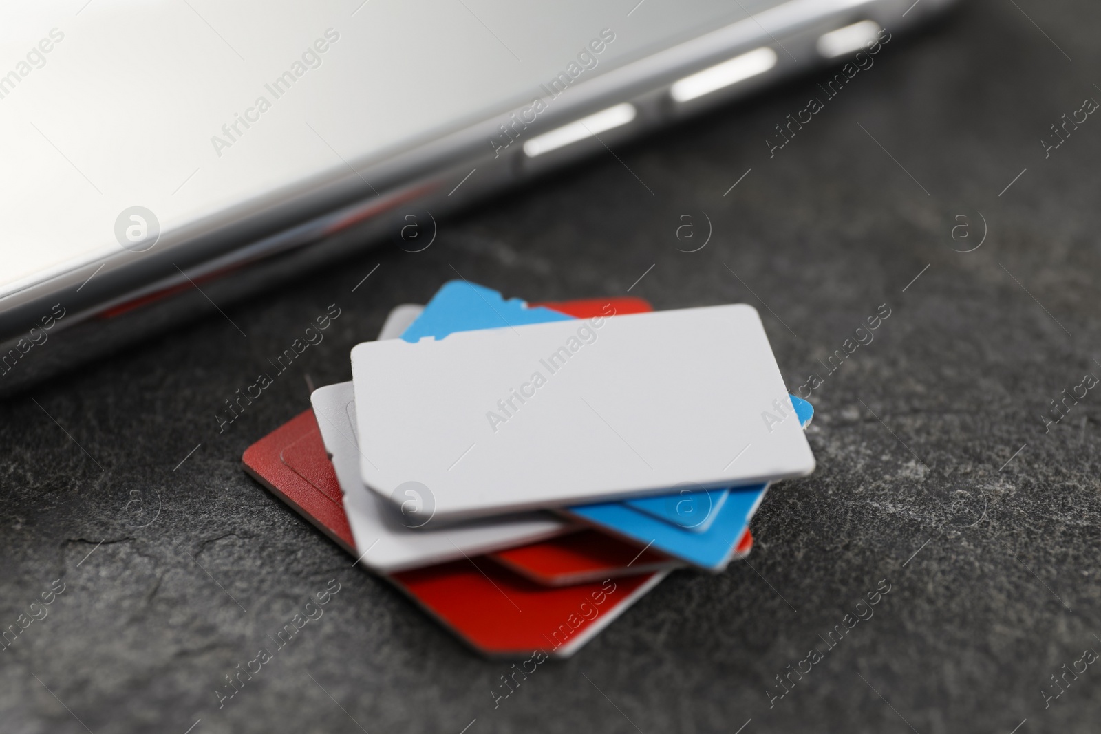 Photo of SIM cards and mobile phone on grey table, closeup