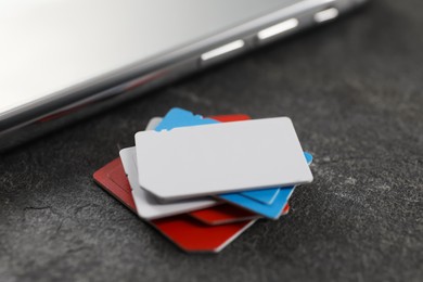 SIM cards and mobile phone on grey table, closeup