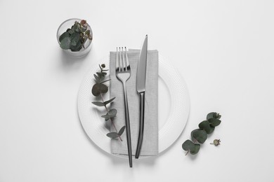 Photo of Stylish setting with cutlery and eucalyptus leaves on white background, top view
