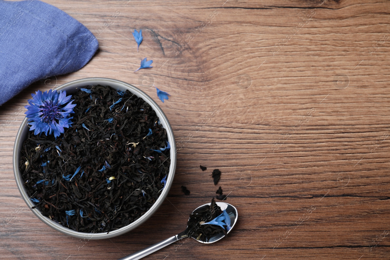 Photo of Dried cornflower tea and fresh flowers on wooden table, flat lay. Space for text