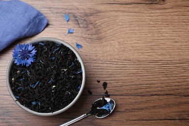 Photo of Dried cornflower tea and fresh flowers on wooden table, flat lay. Space for text