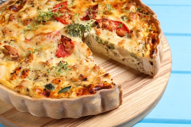 Tasty quiche with tomatoes, microgreens and cheese on light blue wooden table, closeup