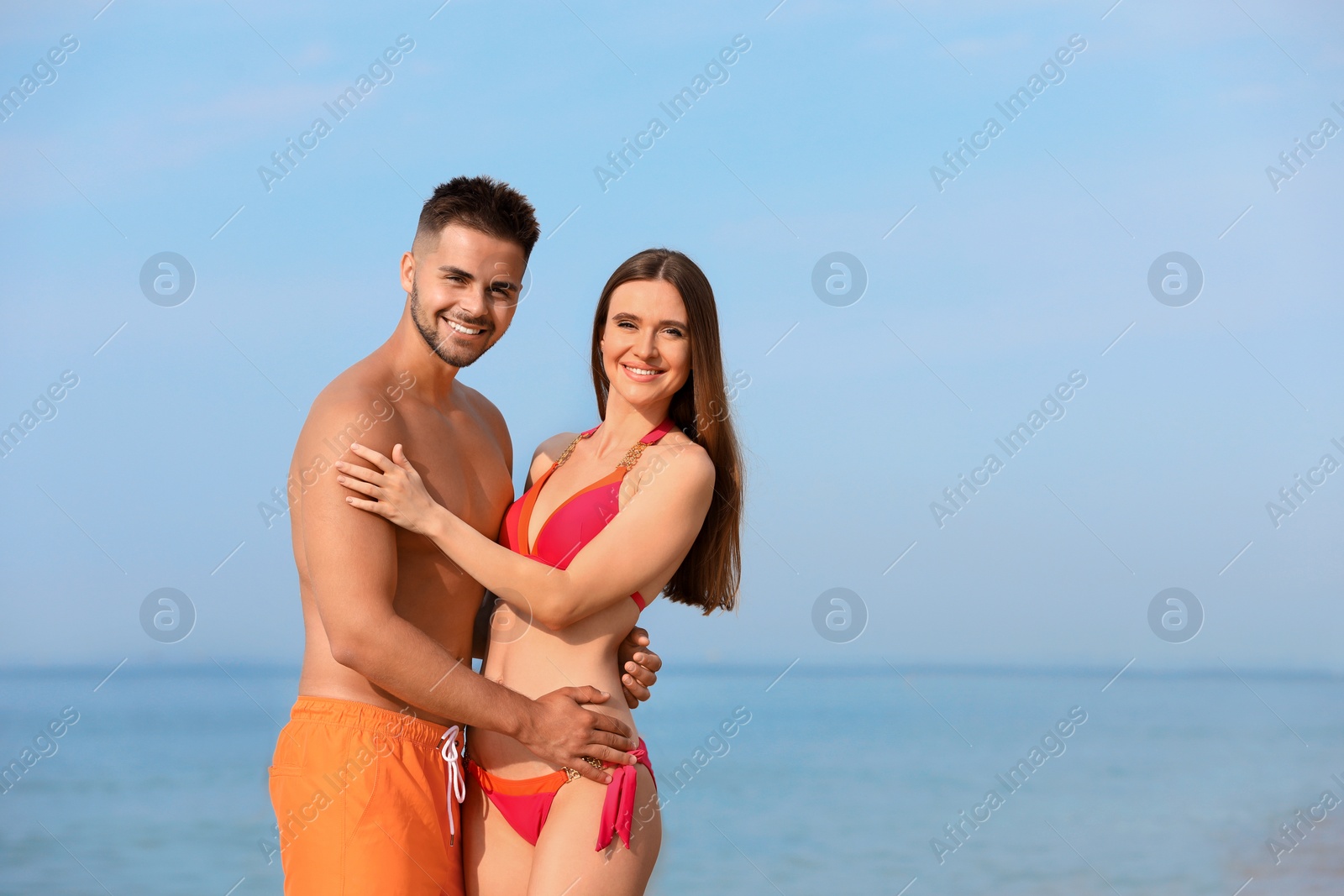 Photo of Young woman in bikini with her boyfriend on beach, space for text. Lovely couple