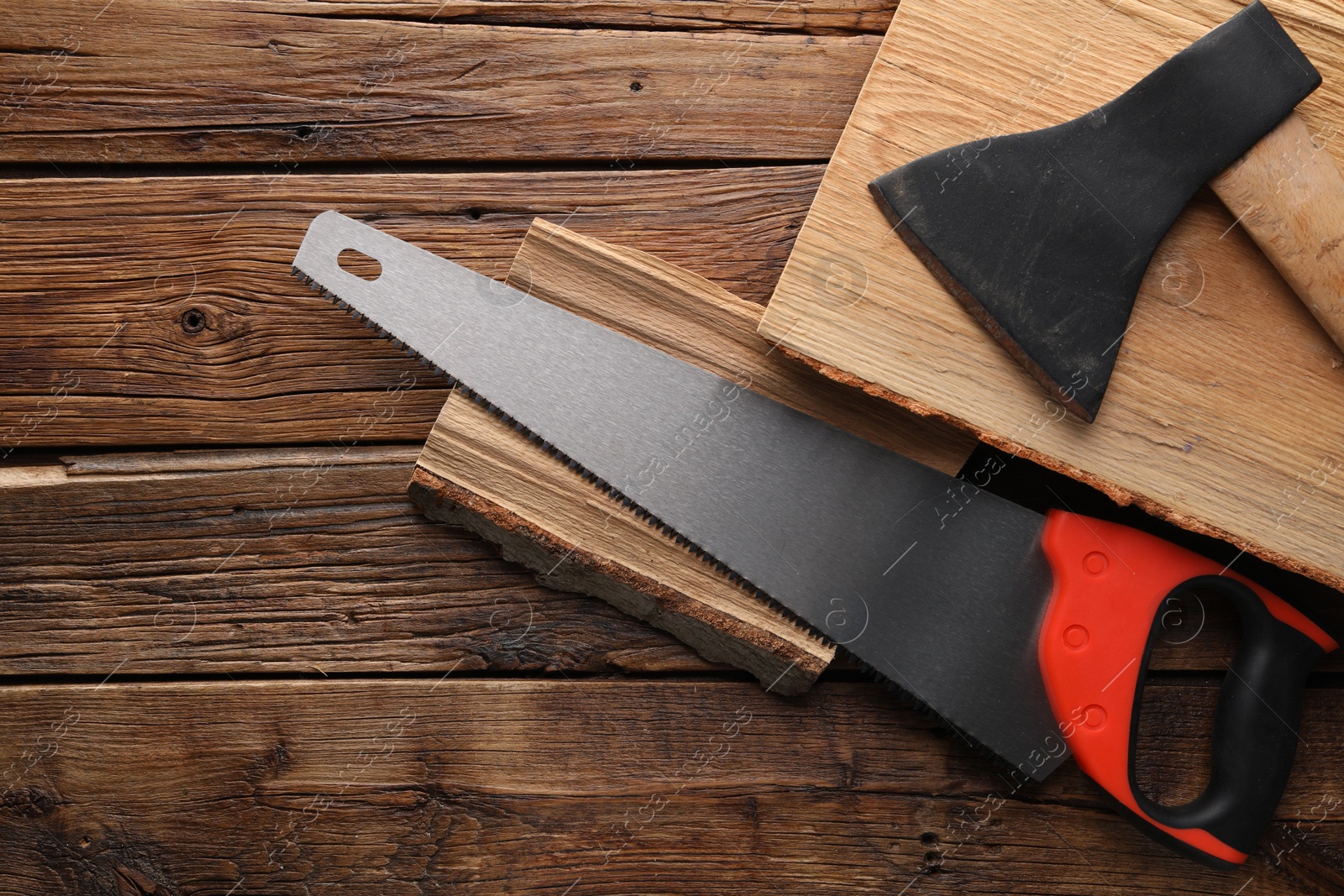 Photo of Saw with colorful handle, axe and logs on wooden background, flat lay. Space for text