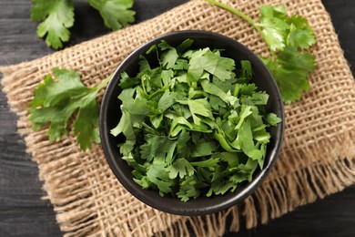 Photo of Cut fresh green cilantro on black table, flat lay