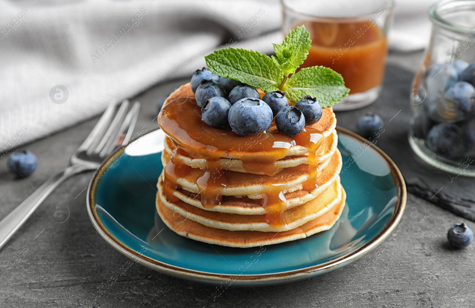 Photo of Delicious pancakes with fresh blueberries and syrup on grey table