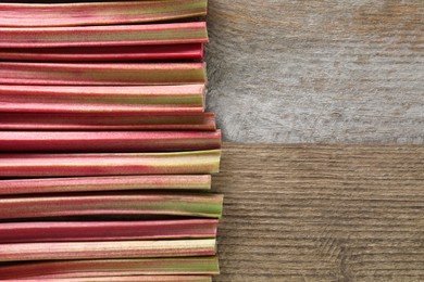 Fresh rhubarb stalks on wooden table, top view. Space for text