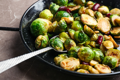 Photo of Delicious roasted brussels sprouts with red beans and peanuts on marble table, closeup