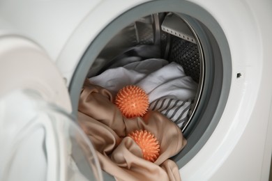 Photo of Dryer balls and clothes in washing machine, closeup