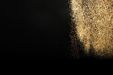 Photo of Shiny golden glitter falling down on black background, space for text. Bokeh effect