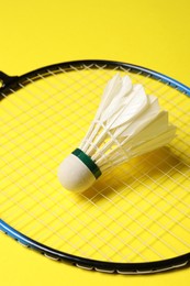 Feather badminton shuttlecock and racket on yellow background