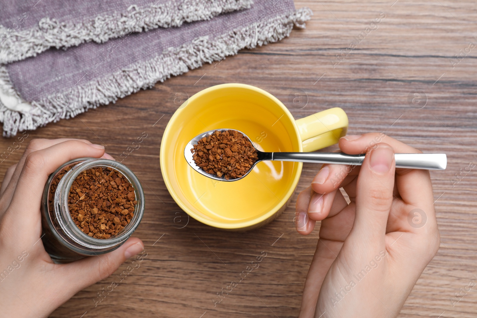 Photo of Woman pouring instant coffee into cup at wooden table, top view