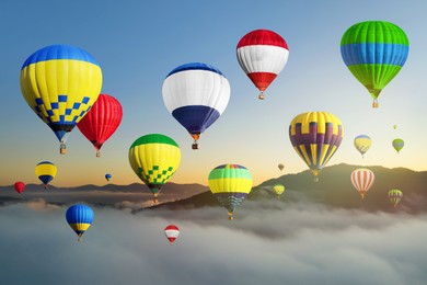 Image of Bright hot air balloons flying over misty mountain at sunrise