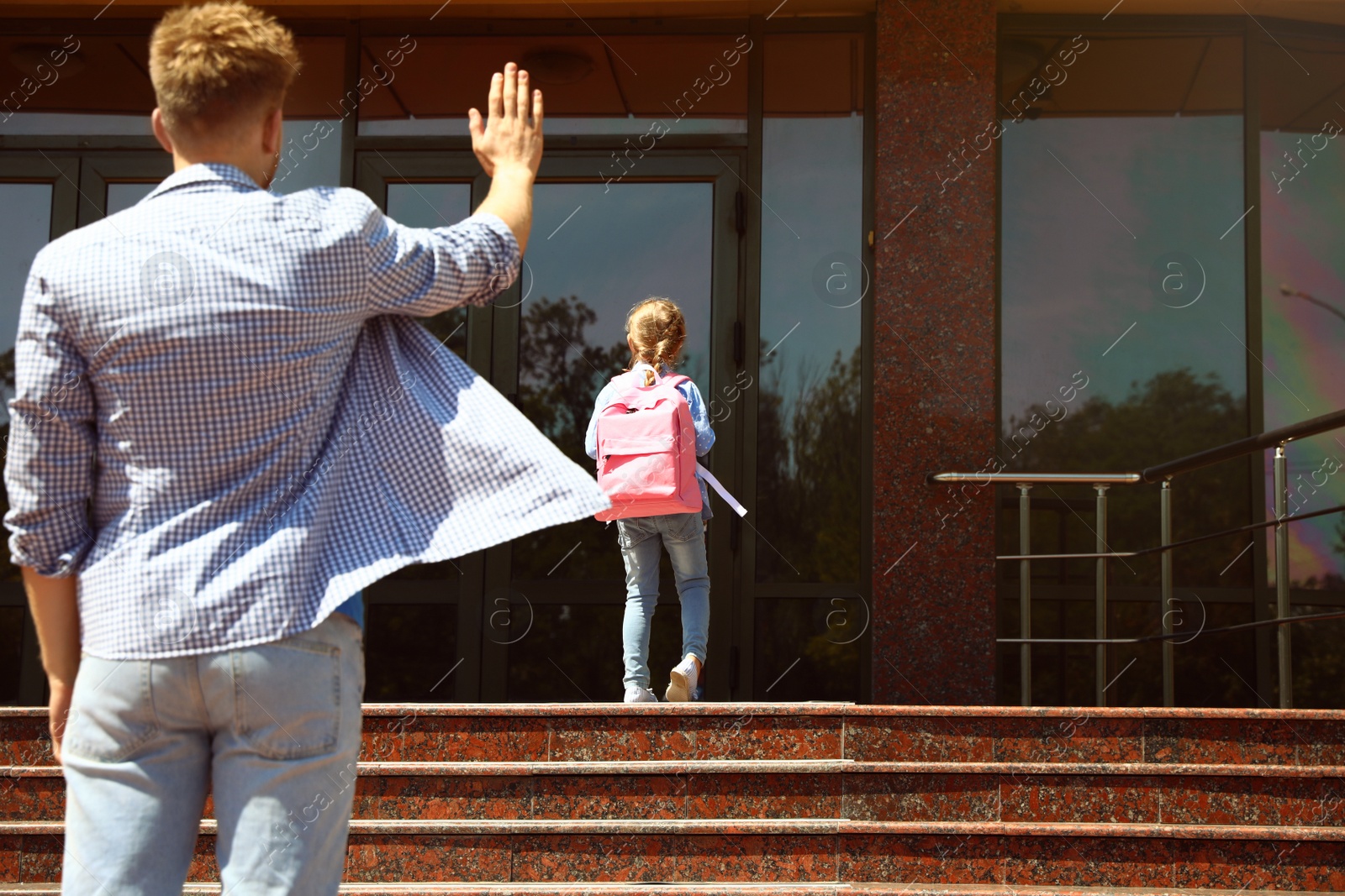 Photo of Young father seeing his little child off to school outdoors