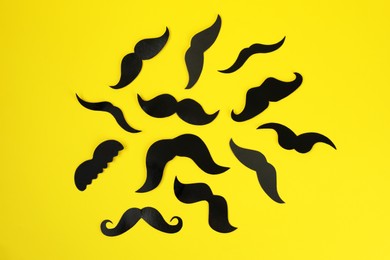 Photo of Fake paper mustaches on yellow background, flat lay