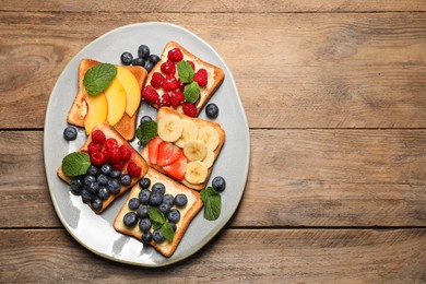 Tasty toasts with different spreads and fruits on wooden table, top view. Space for text