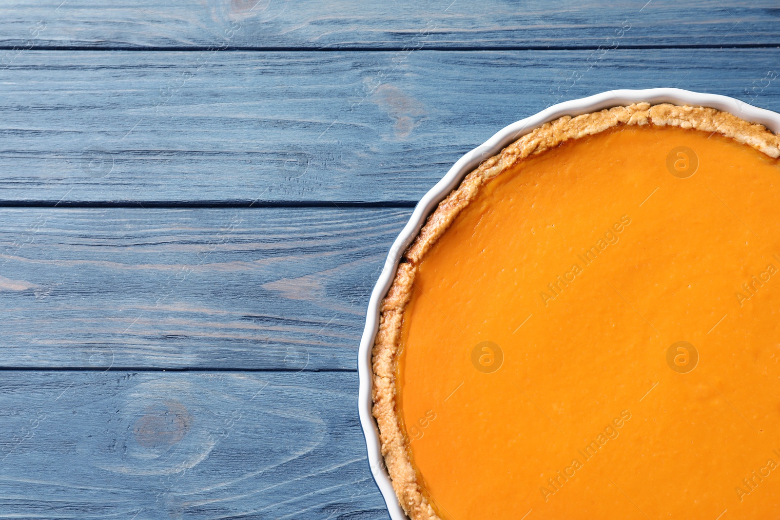 Photo of Fresh delicious homemade pumpkin pie on wooden background, top view with space for text