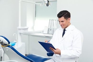 Photo of Portrait of professional male dentist with clipboard in clinic. Space for text