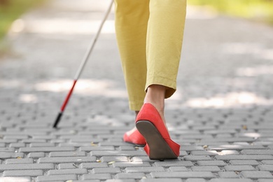 Photo of Blind woman with cane walking on city street, closeup