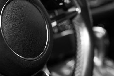 Steering wheel inside of black modern car, closeup