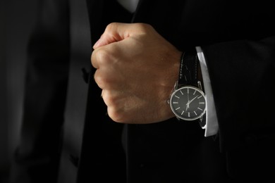 Photo of Businessman with luxury wrist watch on blurred background, closeup