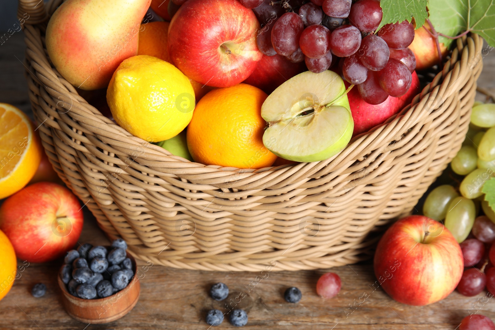 Photo of Wicker basket with different fruits and berries on wooden table, closeup