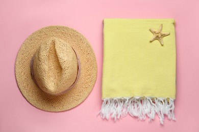 Photo of Beach towel and straw hat on pink background, flat lay