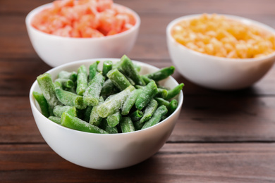 Photo of Different tasty frozen vegetables on wooden table