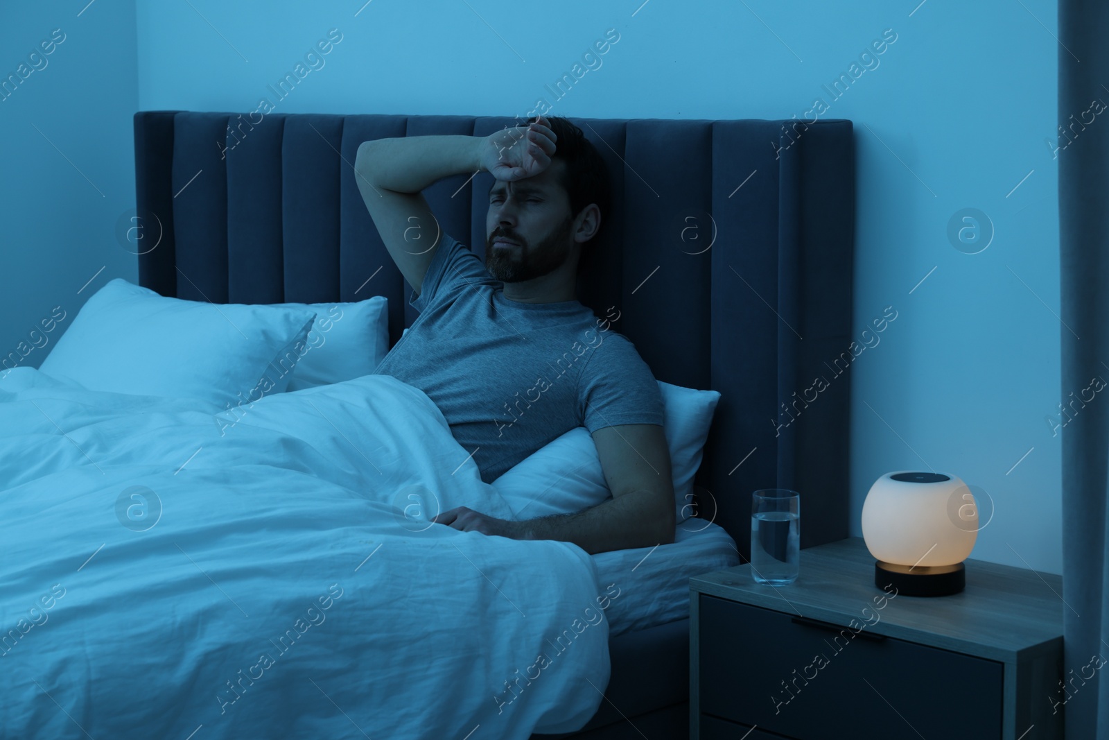 Photo of Man suffering from headache in bed at night