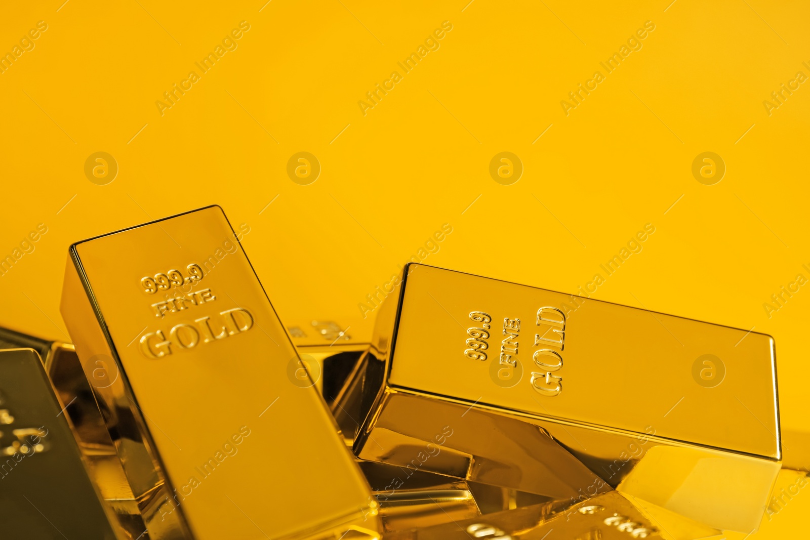 Photo of Many shiny gold bars on orange background, closeup. Space for text