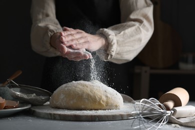 Photo of Making dough. Woman adding flour at grey table, closeup