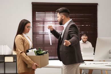 Boss dismissing young woman from work in office