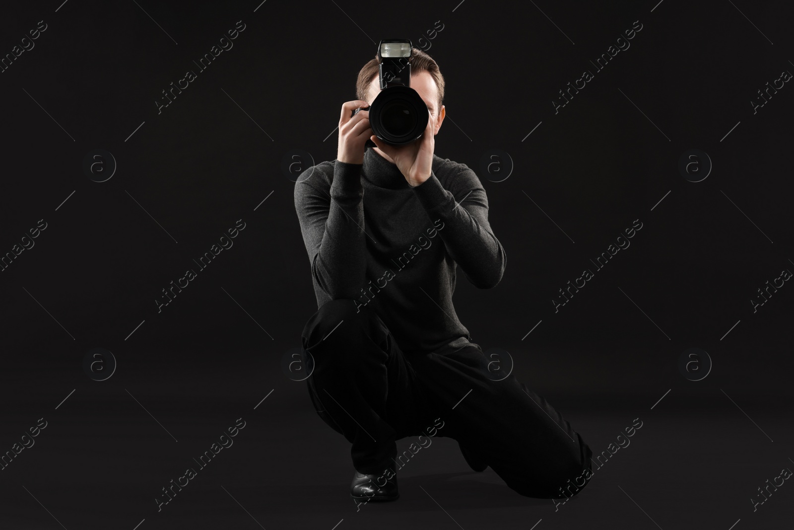 Photo of Professional photographer taking picture on black background